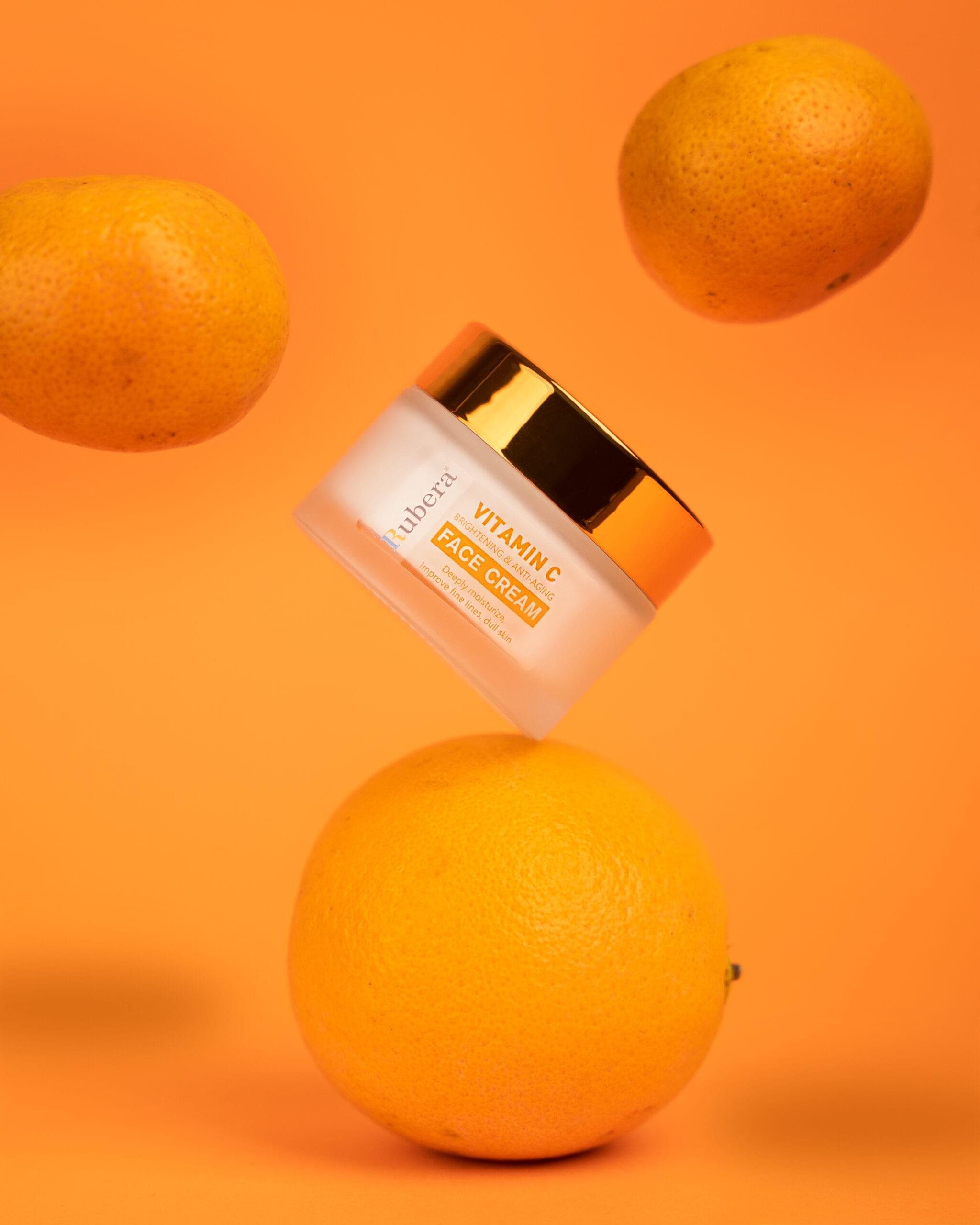 Vitamin C Ultimate Cream| For Better Skin| Face Cream (50g) 1 Vitamin C face cream in a glass jar with an orange lid, surrounded by fresh orange slices and green leaves on a beige background. The text on the image says 'FACE CREME – Shop Now