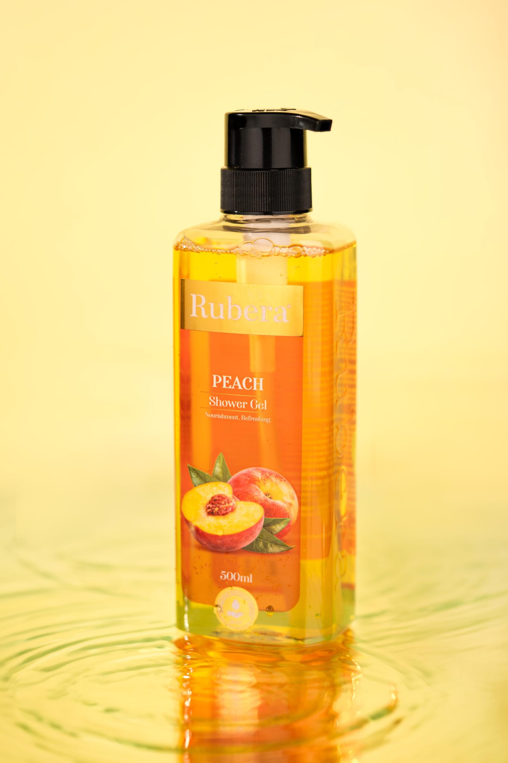 Rubera Peach Shower Scrub – 1000ml bottle with an exfoliating formula, featuring a peach-themed label, placed against a soft satin background with warm, earthy tones.