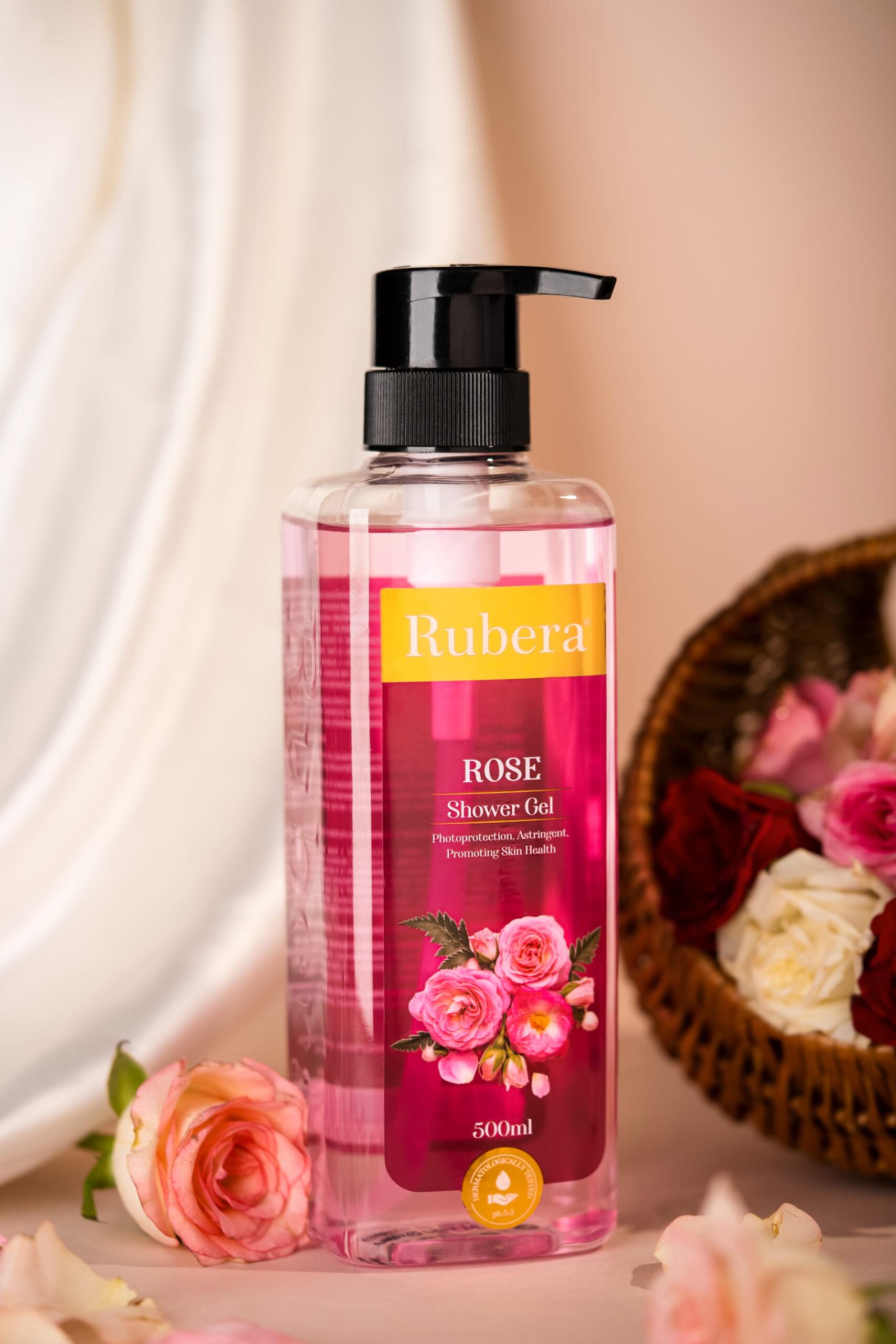 Rubera Rose Shower Gel – 500ml bottle with a pink floral design, placed on a silky fabric with rose petals and fresh roses, creating a luxurious skincare aesthetic.